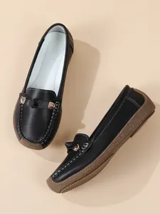 Detail shot of black women's loafers with soft sole and decorative metal buckle.