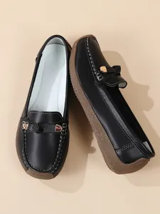 Detail view of black faux leather loafers with decorative hardware and soft gum sole