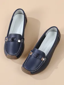 Detail of navy blue leather loafers with white contrast stitching and soft rubber sole