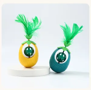Close-up of pineapple-shaped cat tumbler toys featuring green feathers and catnip balls
