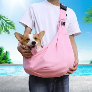 Close-up of a person wearing a pink adjustable pet sling carrier with a happy Corgi inside