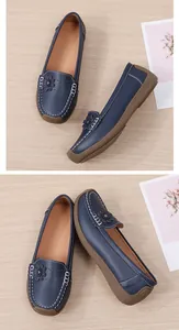 Gedetailleerd zicht op de donkerblauwe loafers met bloemaccenten en witte stiksels.