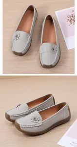 Detailweergave van grijze damesloafers met decoratieve bloem en witte stiksels