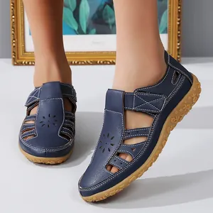 Gros plan de sandales plates ajourées en cuir bleu marine avec semelle fleurie en gomme