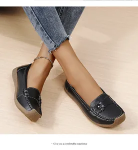 Detail van comfortabele zwarte leren loafers met bloemendecoratie en zachte zool