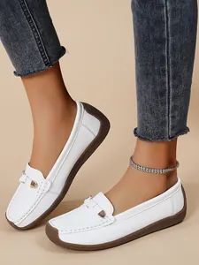 Detailed view of white soft-sole leather loafers with elegant metal buckle decoration