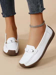 Detailed view of white slip-on loafers with decorative metal buckle and soft sole