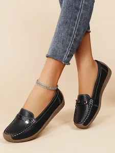 Detail view of black women's loafers featuring white stitching and decorative heart bit