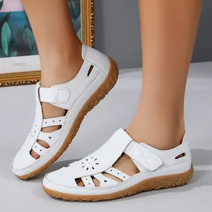Gros plan de sandales plates blanches ajourées pour femmes avec velcro et semelle fleurie.
