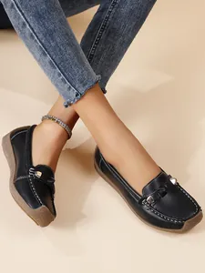Close-up of black leather loafers with soft soles and decorative metallic buckle details