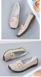 Detail view of beige loafers featuring floral perforations and golden buckle accents