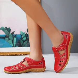 Détail de sandales plates rouges en cuir pour femmes avec des découpes fleuries élégantes
