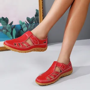 Vue détaillée de sandales plates rouges ajourées pour femme portées par un mannequin