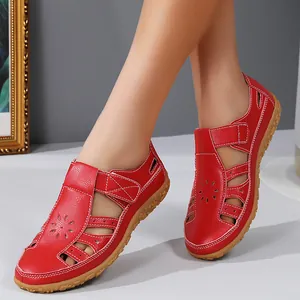 Détail des sandales en cuir rouge ajourées avec brides à scratch pour un style élégant.