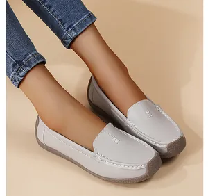 Detalle de mocasines de cuero gris con costuras blancas y suela de goma duradera