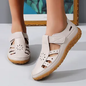 Vue détaillée de sandales plates en cuir beige avec de jolis motifs floraux ajourés