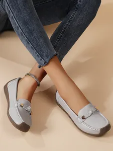 Close-up of comfortable grey loafers with soft soles and decorative metal buckle details.