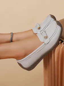 Close-up detail of women's grey soft-sole loafers with gold accents and textured leather finish