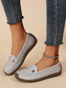 Close-up detail of grey women's slip-on loafers featuring a soft sole and metal buckle