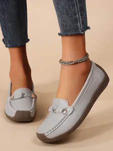 Close-up detail of light gray women's loafers featuring soft soles and metal buckles