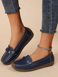 Side view detail of navy blue soft-sole loafers with white stitching and gold buckle