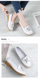 Detail view of white leather loafers for women featuring tassels and a soft wedge sole