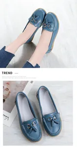 Close-up detail of blue leather loafers for women featuring decorative tassels and metal buckles.