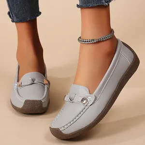 Casual women's grey slip-on loafers featuring a soft brown rubber sole and metallic buckle detail