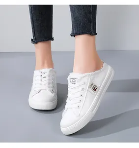Close-up view of stylish white canvas backless sneakers featuring frayed edges and laces
