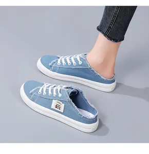 Detailed view of light blue denim canvas mule sneakers with stylish frayed edges