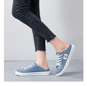 Side view of stylish blue denim canvas mule sneakers with white laces and frayed edge details