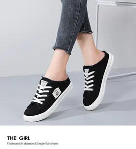 Close-up of black canvas backless sneakers with frayed edges and white laces