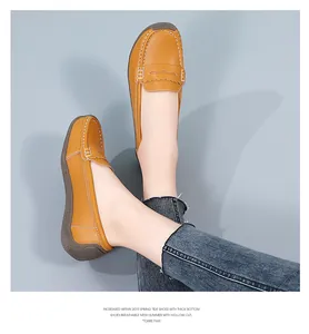 Detail of comfortable mustard yellow leather loafers with white stitching on feet