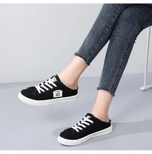 Detailed close-up of black canvas mule sneakers with white laces worn by a model