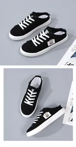 Close-up detail of black canvas mule sneakers featuring fringed edges and white laces