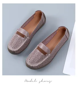 Close-up van mauve lederen loafers met geometrische uitgesneden patronen en witte stiksels.
