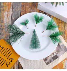 Vue détaillée des aiguilles de pin artificielles et d'un mini sapin de Noël sur une assiette blanche