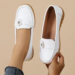 Detail view of stylish white women's loafers with floral decoration and gum sole.