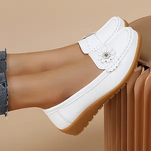 Detailed side view of white leather loafers for women featuring elegant floral decoration