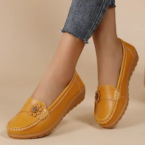 Detail view of mustard yellow leather loafers with a delicate floral toe decoration