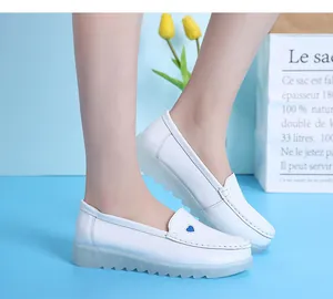Gros plan sur des chaussures d'infirmière en cuir blanc avec broderie cœur bleu.