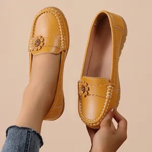 Detail of women's yellow leather loafers featuring flower accents and white stitching
