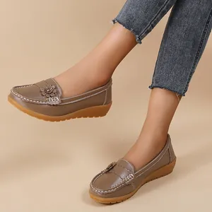 Detailed view of brown leather loafers with flower decoration and white stitching