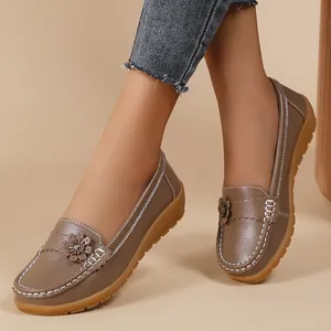 Close-up of brown women's loafers featuring floral accents and white contrast stitching.