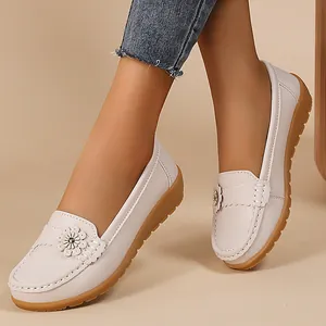 Close-up detail of white faux leather loafers with floral applique and soft sole