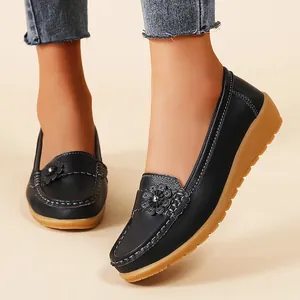 Close-up of black floral loafers with textured finish and durable brown rubber sole