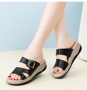Nahaufnahme schwarzer Keilsandalen für Damen mit goldener Schnalle und weicher Sohle