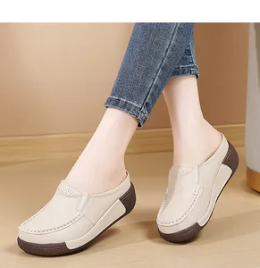 Gros plan de mocassins à plateforme beiges portés avec un jean sur parquet.
