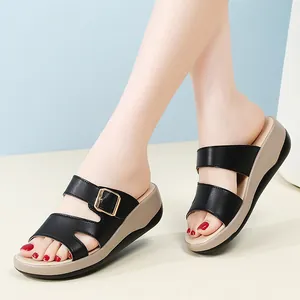 Damen-Keilsandalen in Schwarz mit goldener Schnalle und weicher Plateausohle.