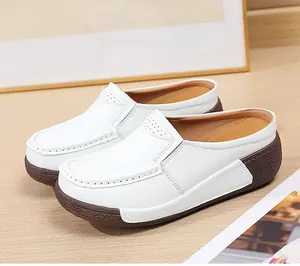 Gros plan de mules à plateforme blanches avec un design perforé et un talon compensé